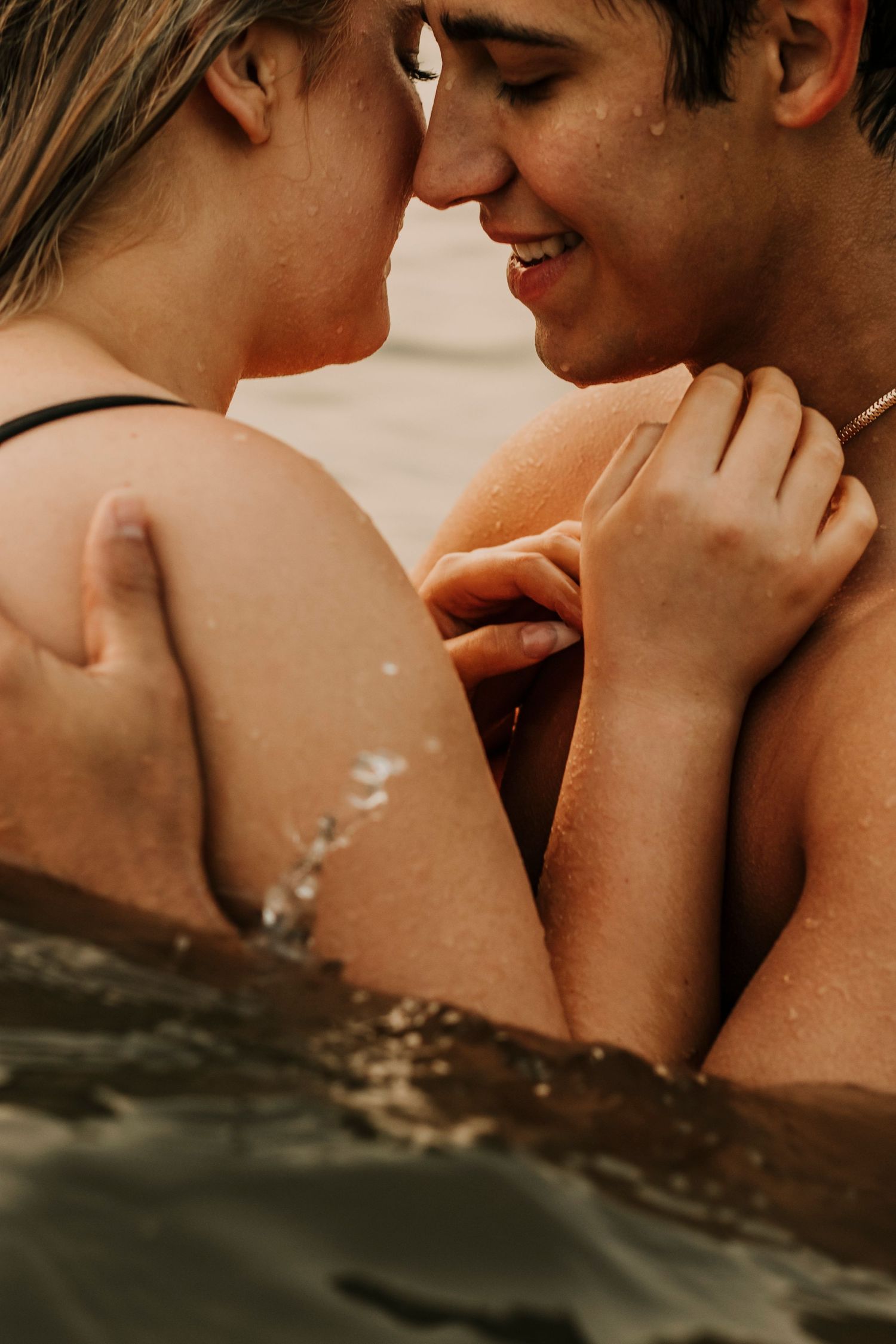 Close-up of couple sharing an intimate moment in water during golden hour.