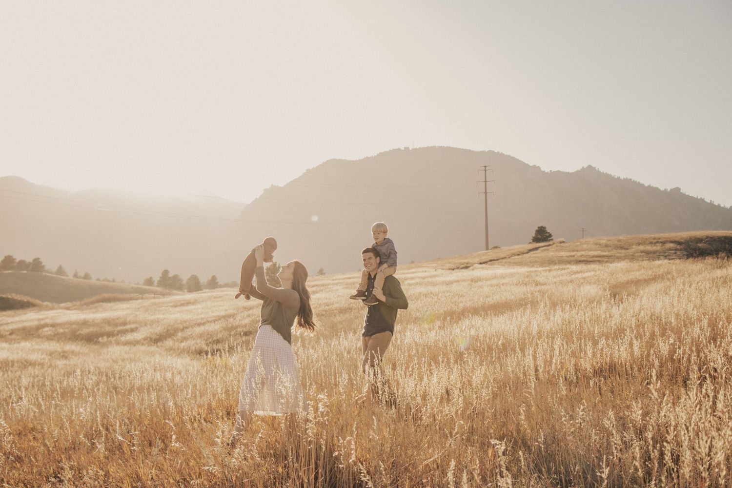 Silhouettes of family members walking through golden grass field at sunset.