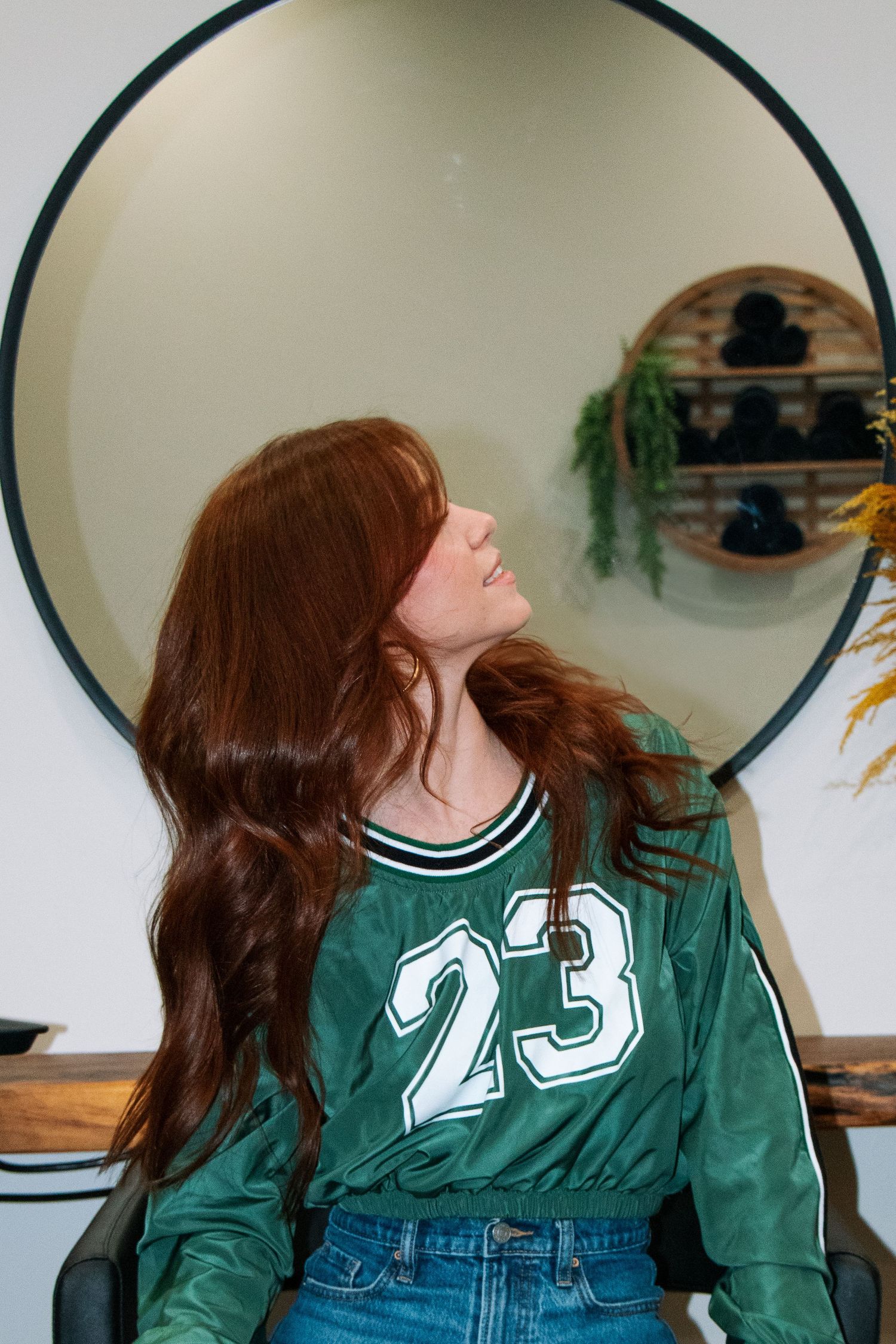 Series of branding poses showing person in green jersey number 23 and jeans against a white wall with circular decor piece.