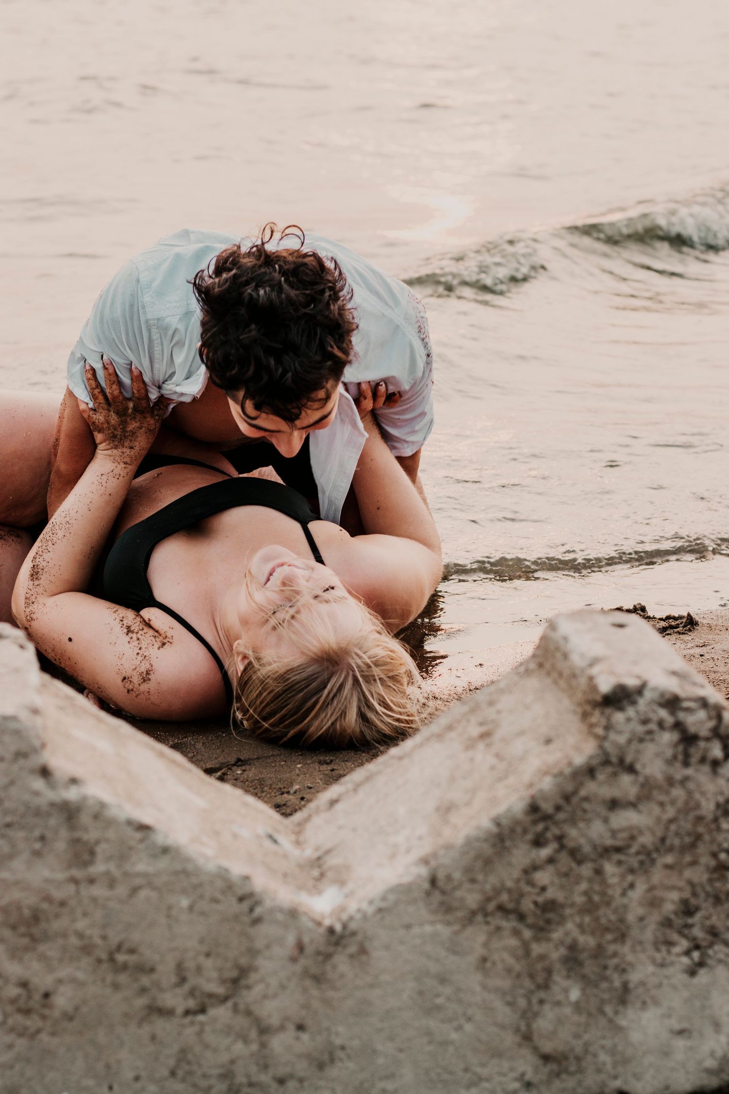 Romantic couple lying in a heart drawn in the sand at the beach during sunset.