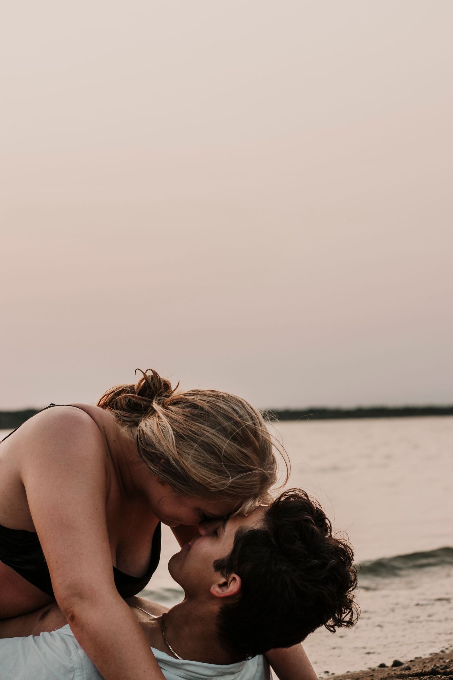 Intimate couple sharing a tender moment on a beach at dusk.