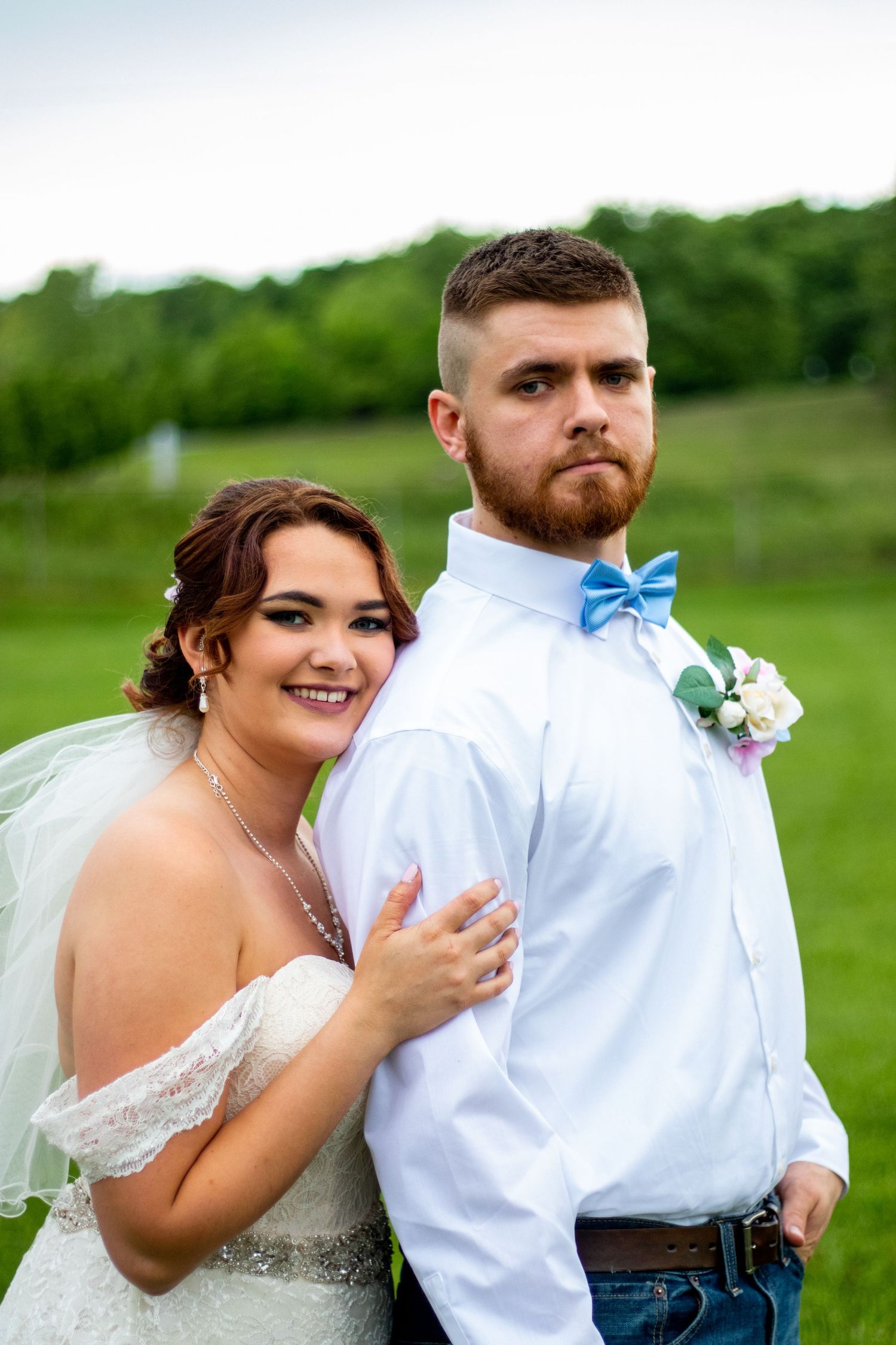 Joyful outdoor wedding portrait with couple in casual elegant attire.