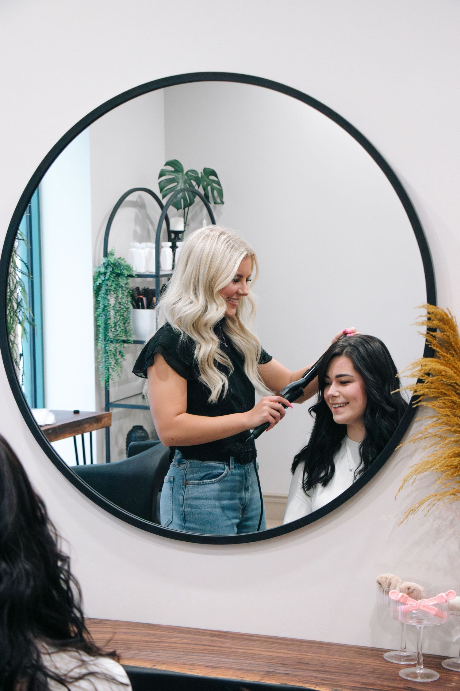 Stylish round mirror reflection showing hair styling branding session in modern salon.