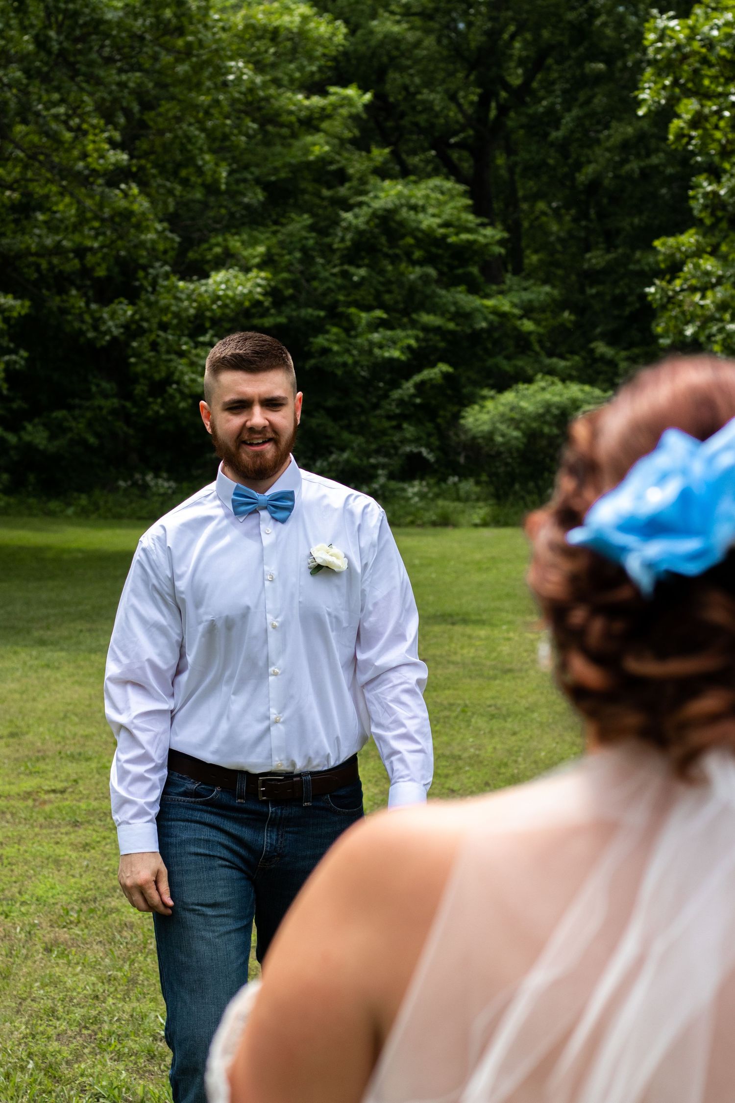 First look wedding moment captured outdoors in a natural green setting.