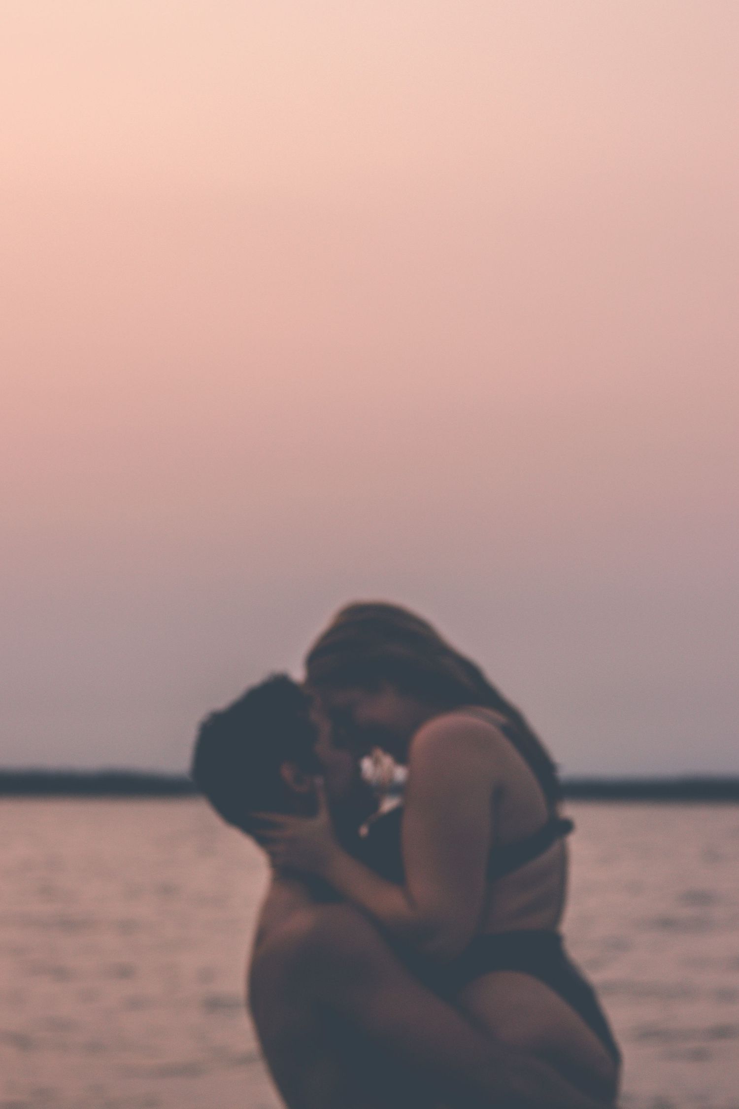 Couple sharing romantic moment in water during dusky sunset.