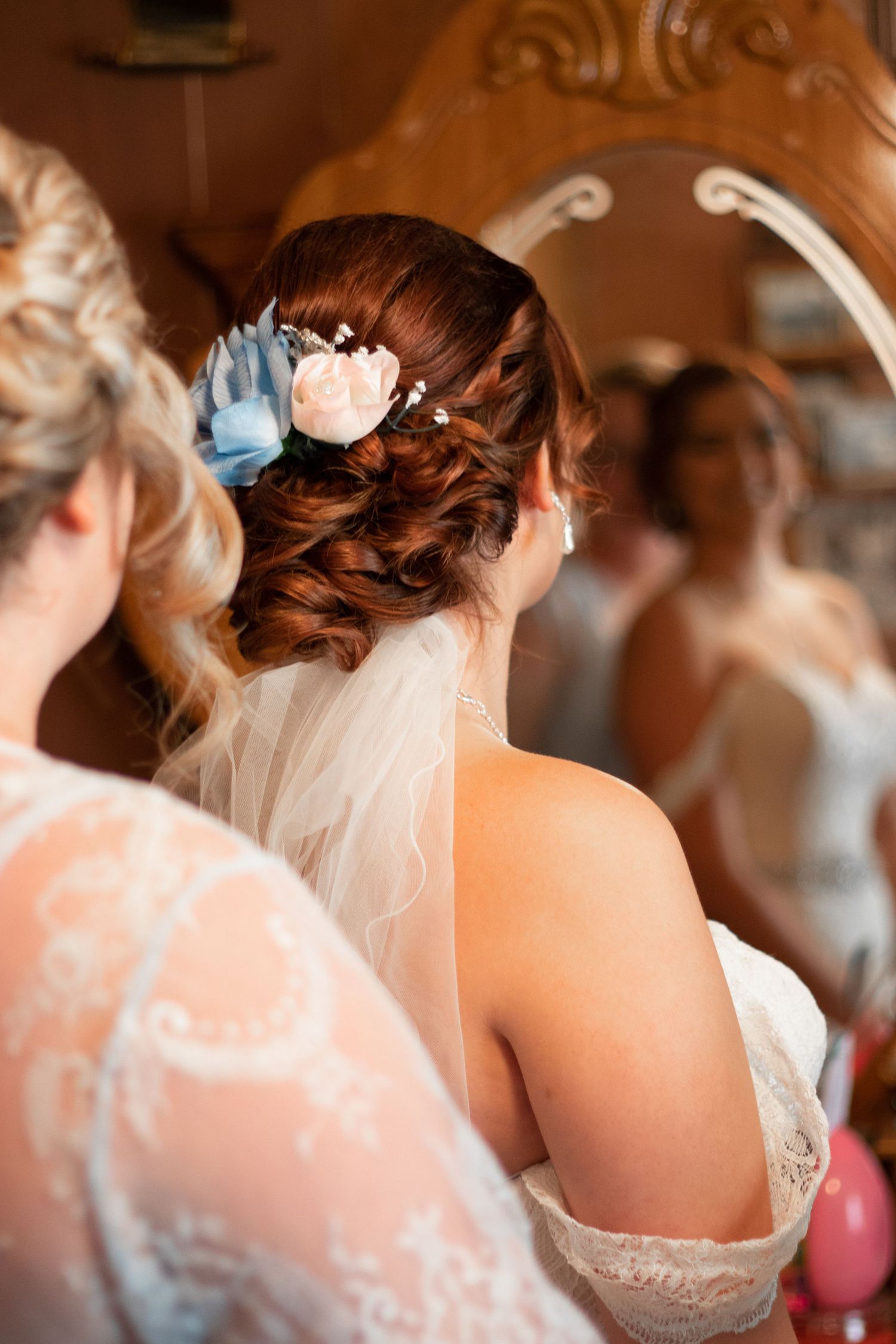 Close-up of bride's elegant updo hairstyle with blue flower and veil details.