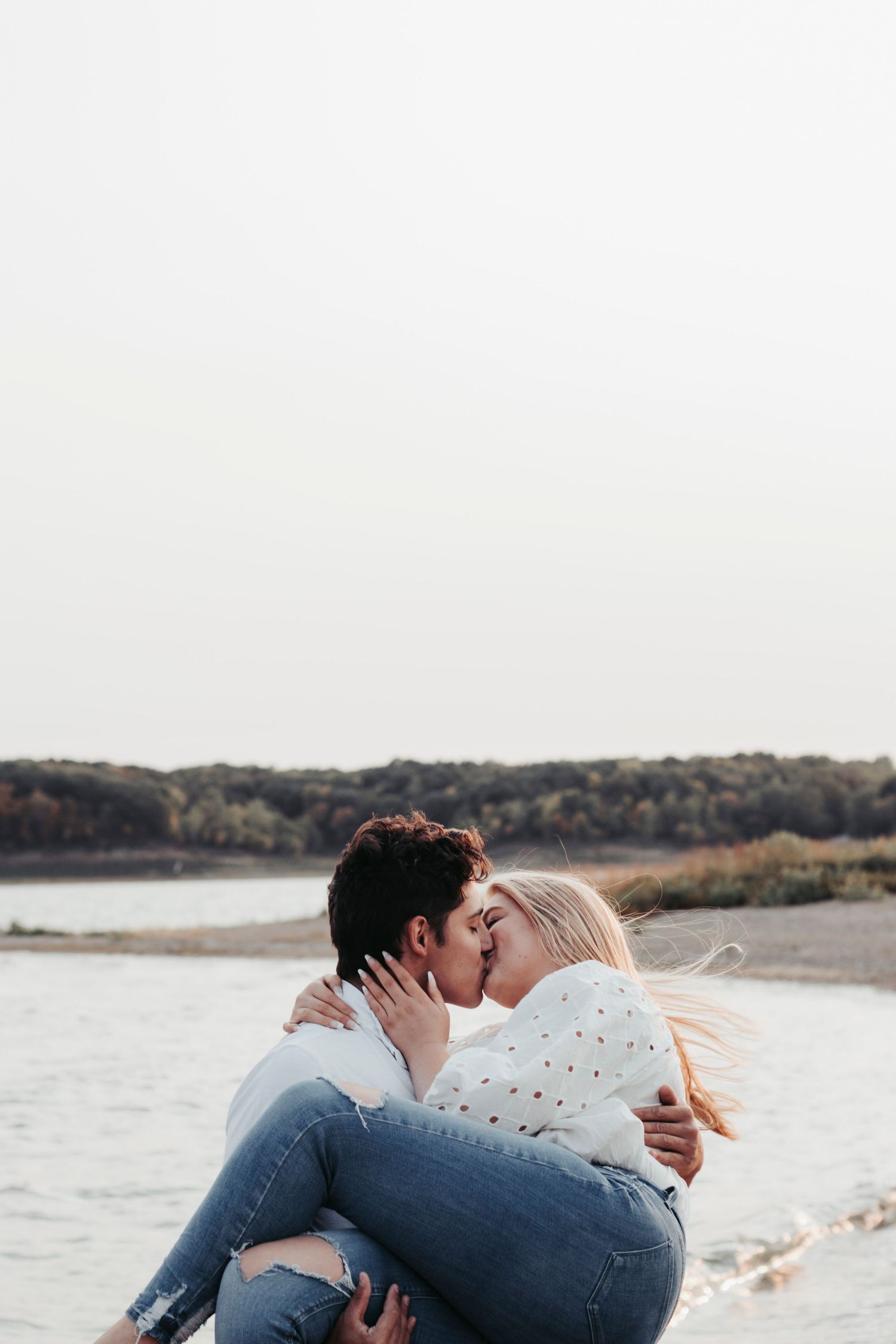 A romantic beach scene with a couple sharing an intimate moment near the water.