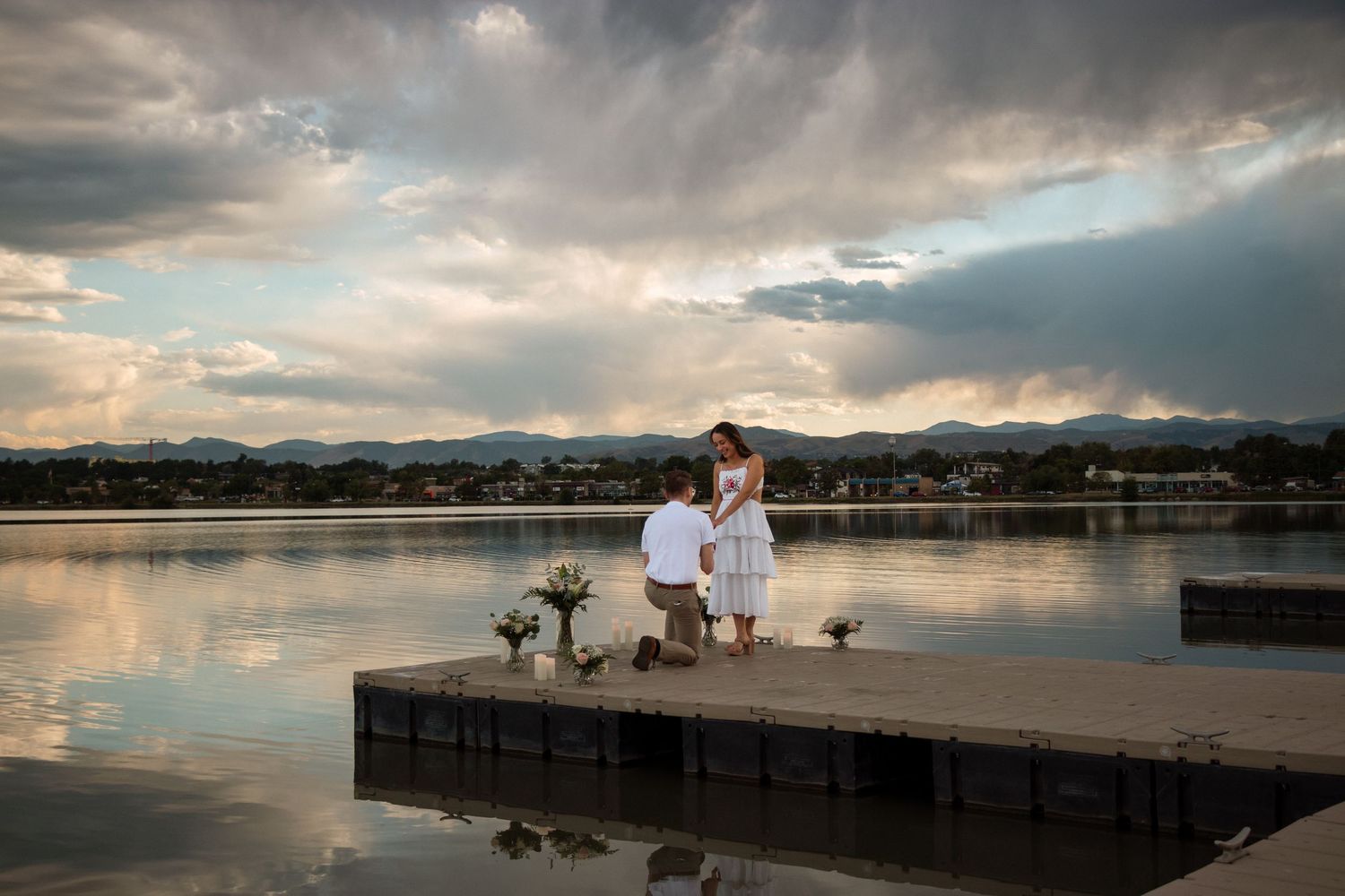 A serene lake landscape with dramatic clouds reflecting on the calm water's surface during golden hour.