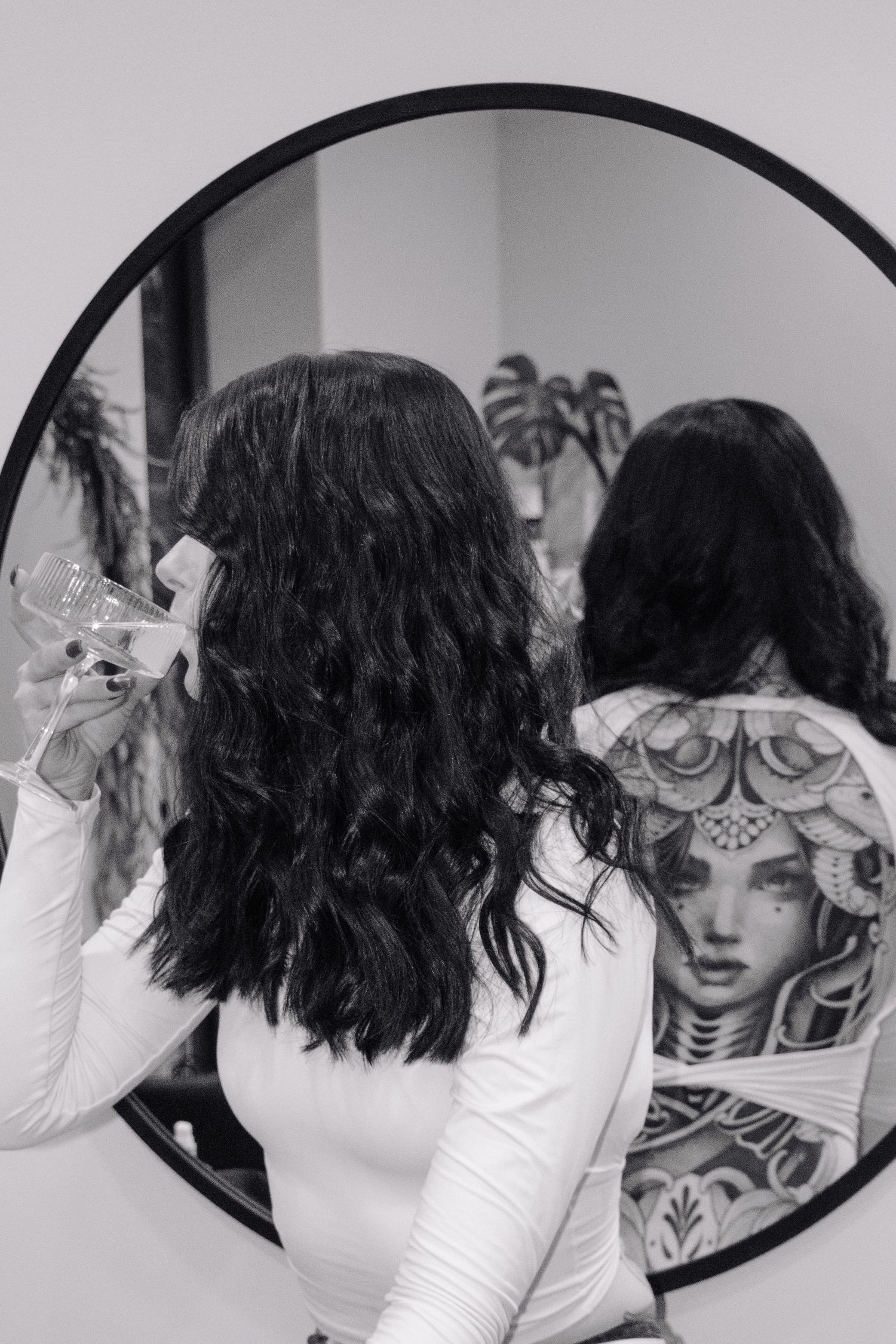 Back view of tattoo art reflected in round mirror during hair styling branding.
