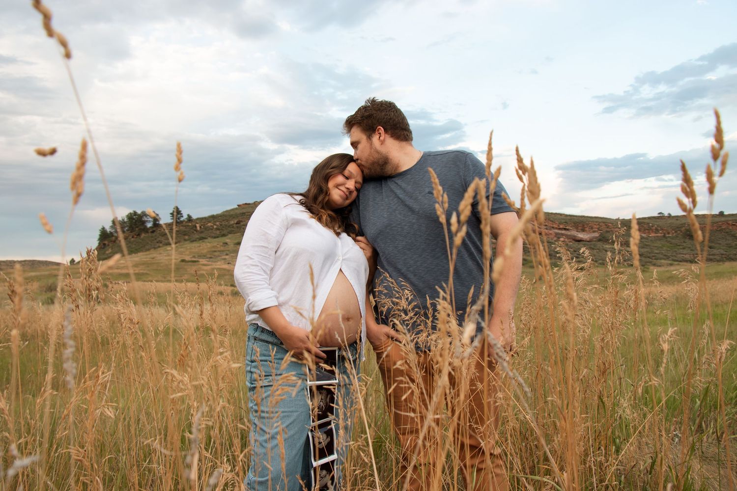 A couple shares a romantic moment together in a golden wheat field during sunset.