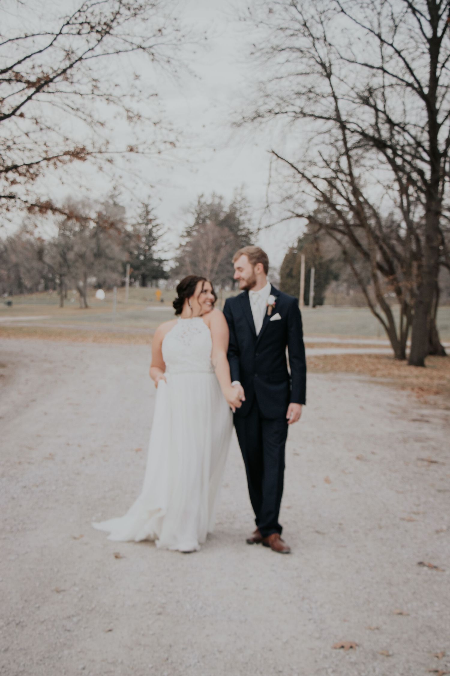 Wedding couple poses in a dreamy winter landscape with bare trees.