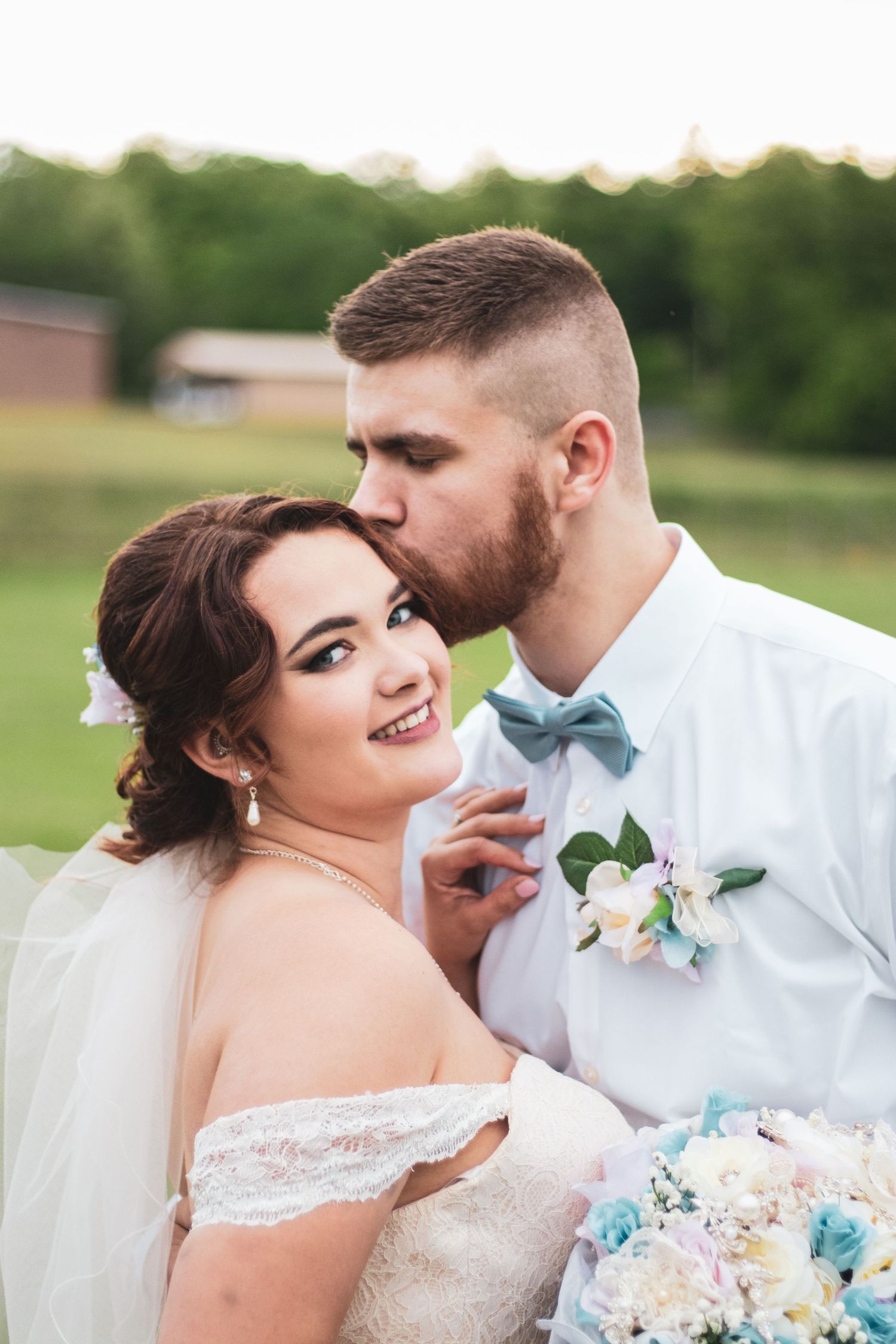 A romantic outdoor wedding portrait showcasing elegant bridal fashion and floral details.