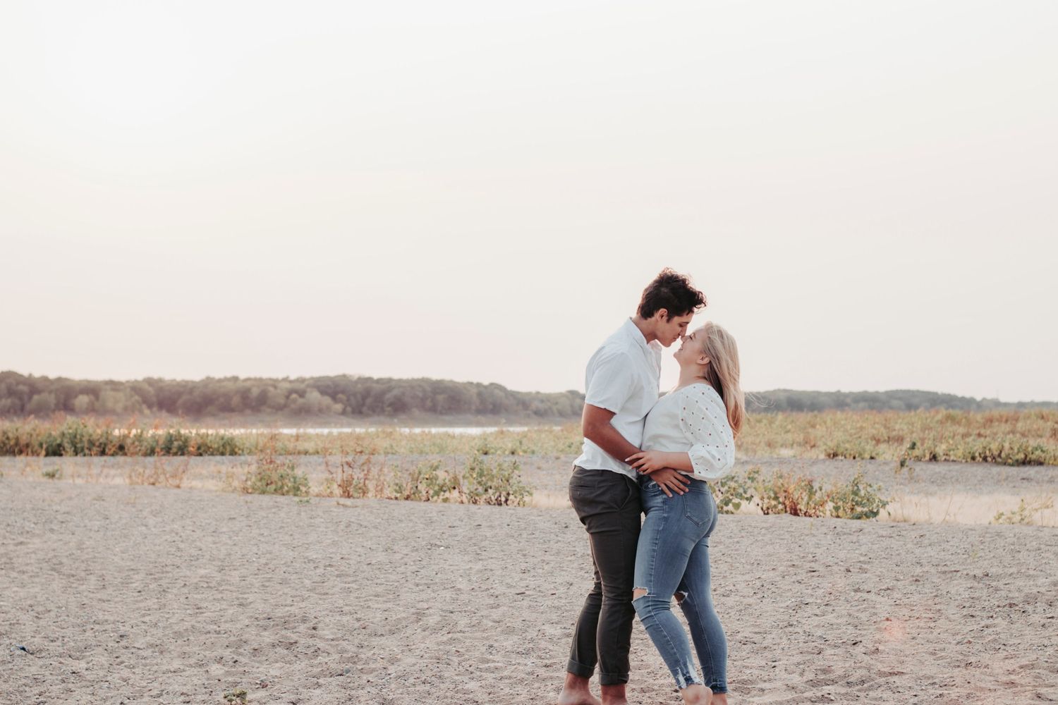 A couple shares a romantic moment on the beach at dusk.