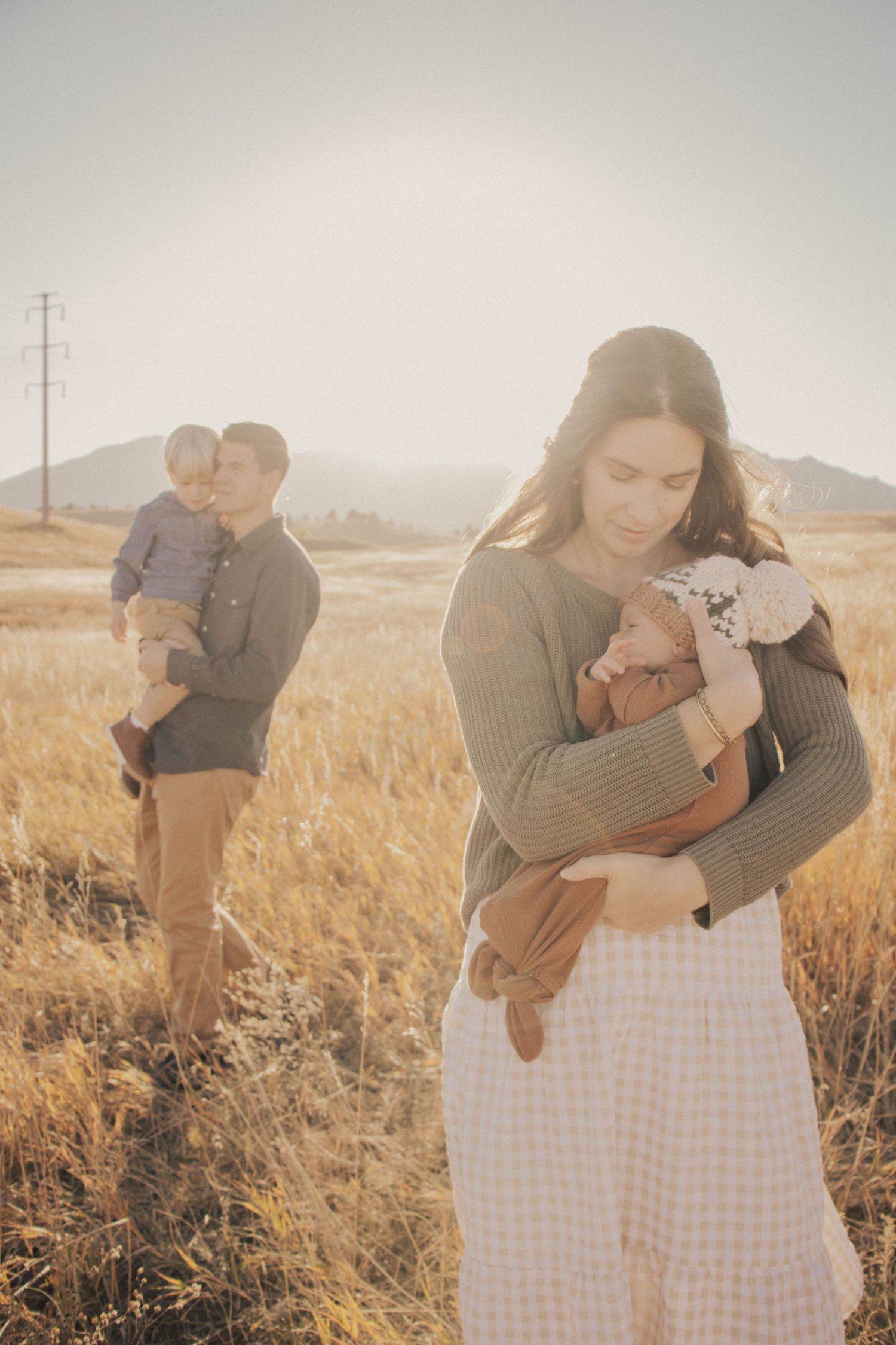 Family portrait in golden field with baby and child at sunset.