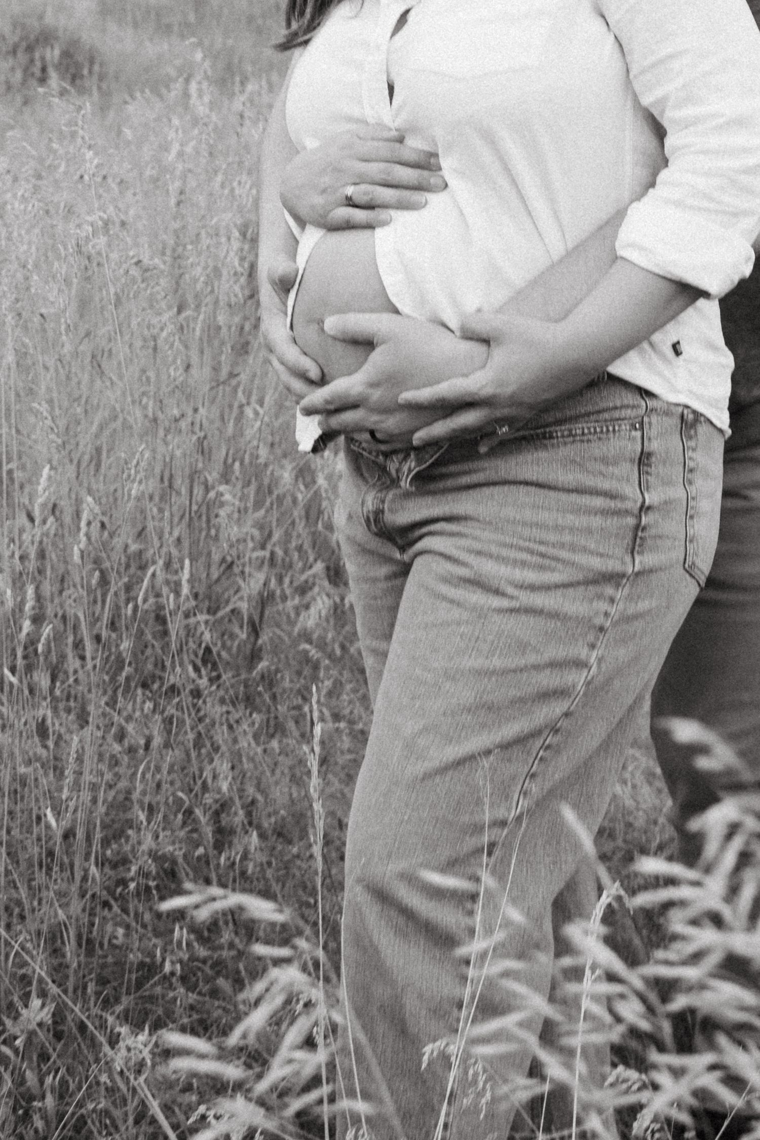 Black and white pregnancy progression photos showing a growing baby bump in a grassy outdoor setting.