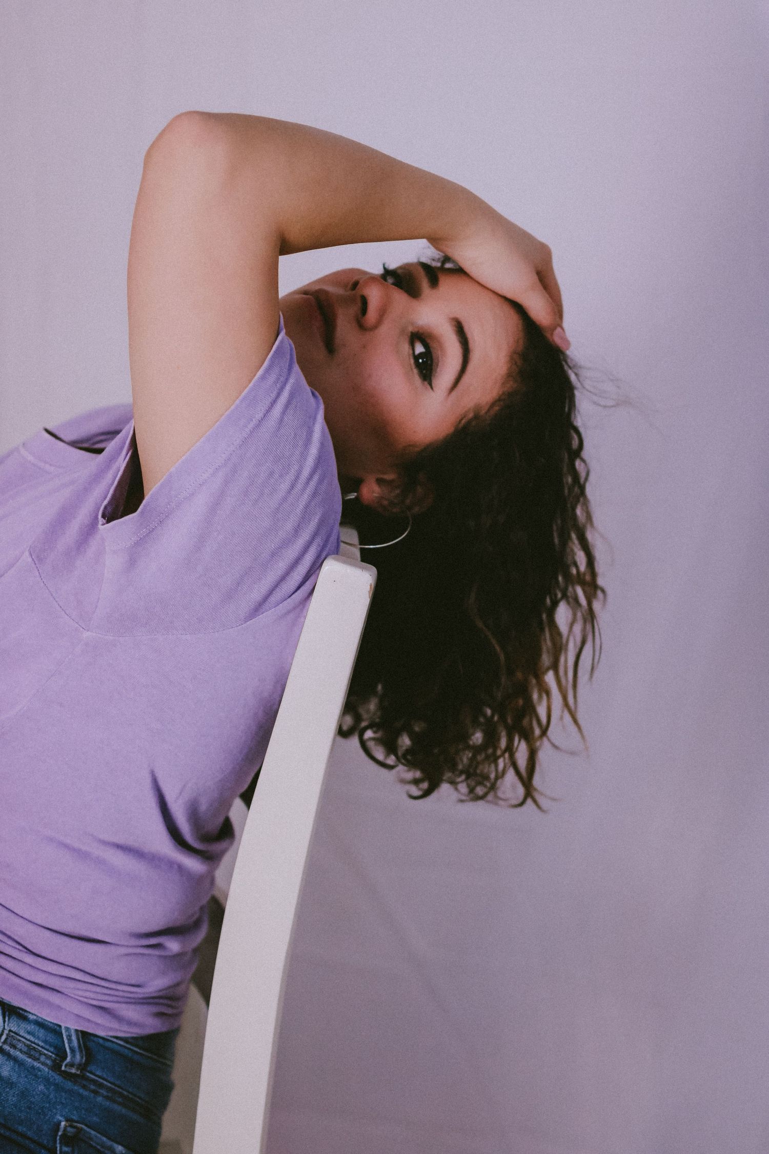 Artistic portrait with purple t-shirt against lavender background showing dramatic pose.