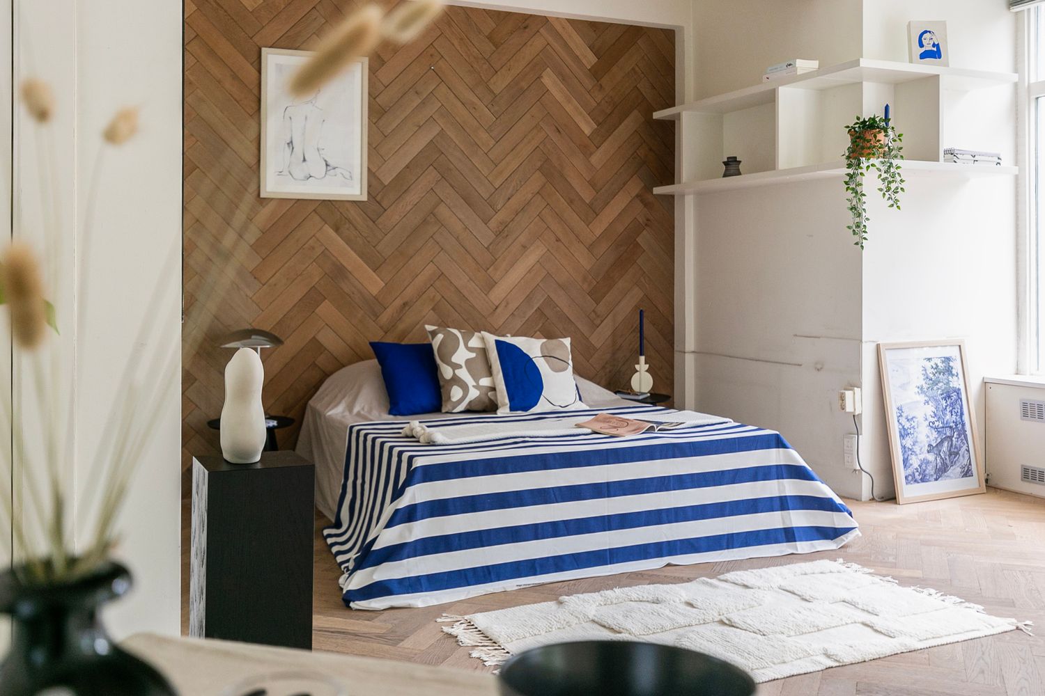 Cozy bedroom with herringbone wood accent wall and blue striped bedding.