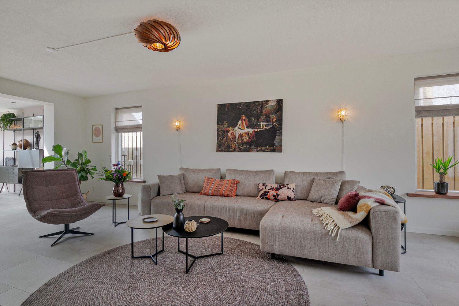 Contemporary living room with grey sectional sofa, round coffee tables, and modern wall art.