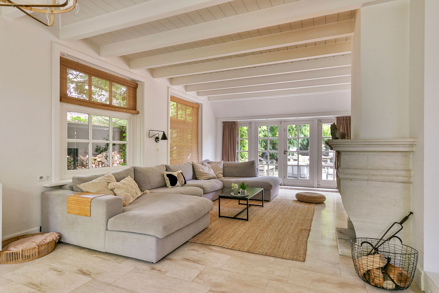 Bright living room with large sectional sofa, exposed beams, and French doors leading to outdoor space.
