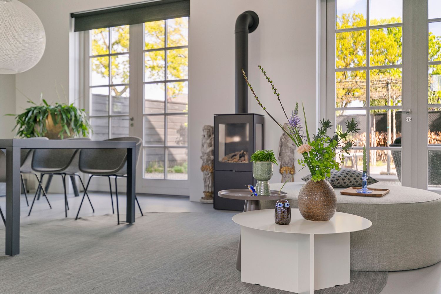 Bright contemporary living space with wood stove, dining area and large windows letting in natural light.