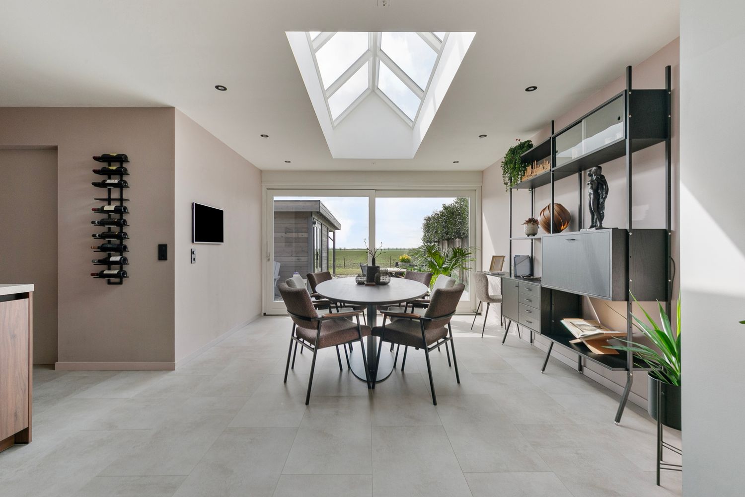 Modern dining room with rectangular skylight, grey chairs, and black metal shelving unit.