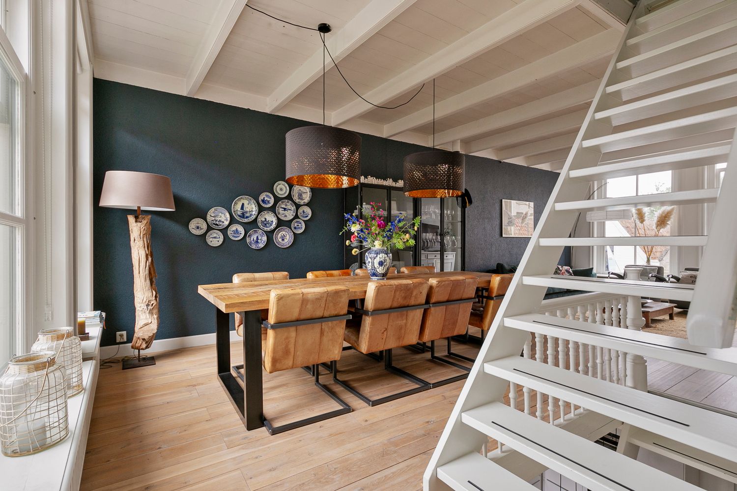Rustic dining area with wooden table, black accent wall, and decorative plate display.