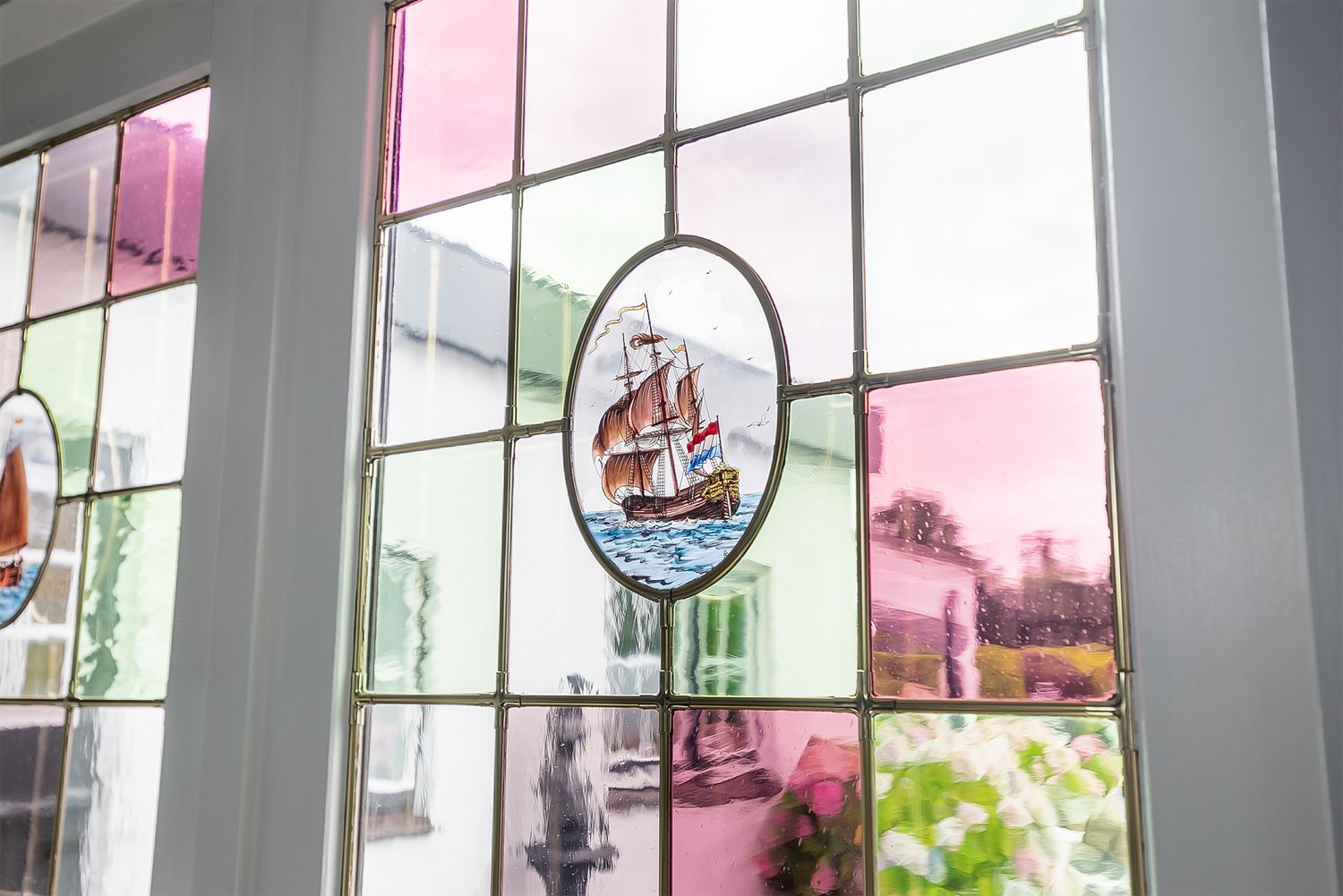 Vintage stained glass window medallion featuring a sailing ship design.