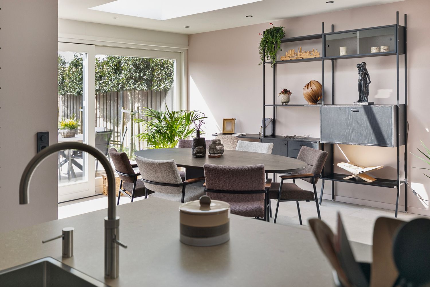 Modern open concept dining area with industrial shelving and large windows bringing in natural light.