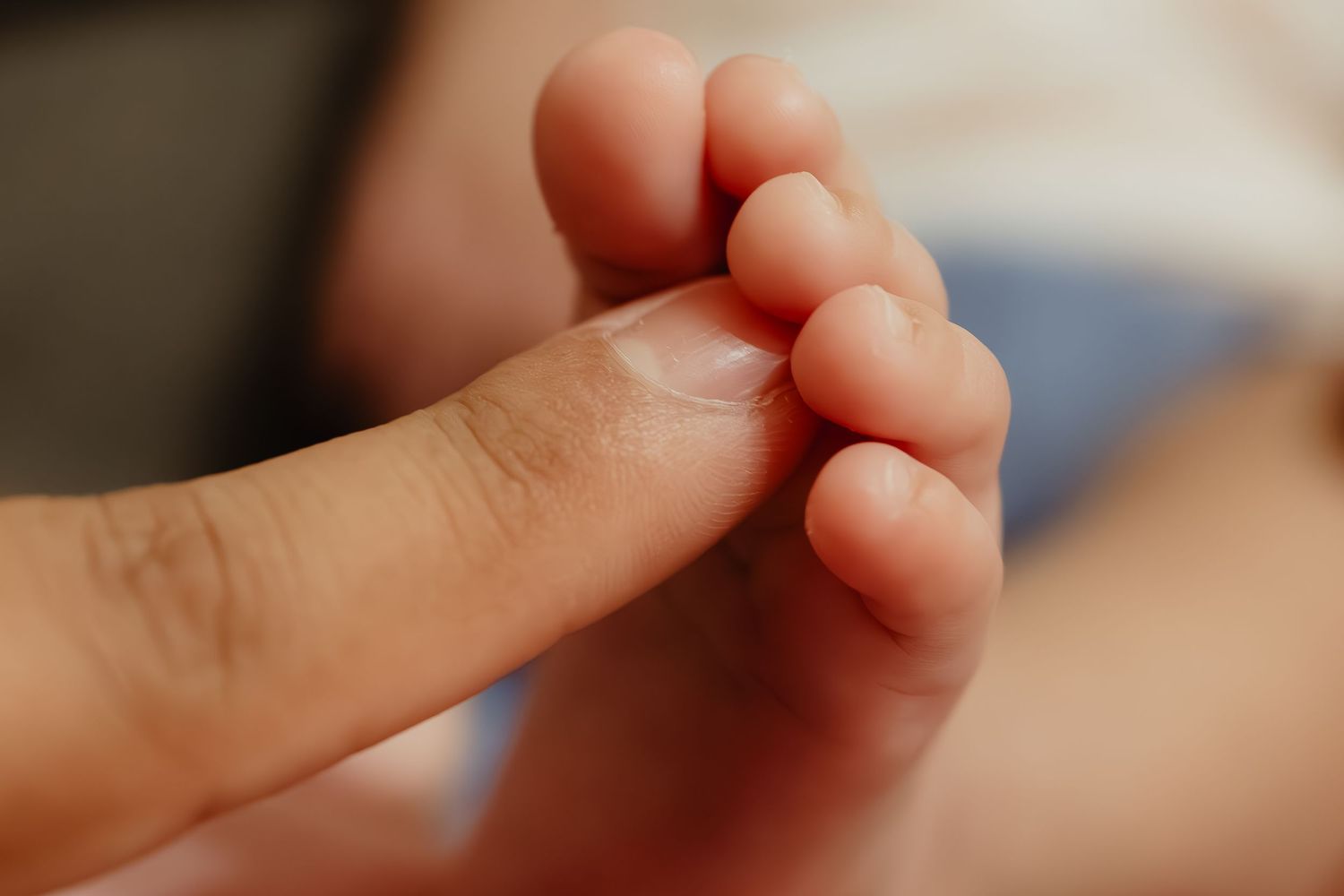 Tiny baby fingers grasping an adult's finger in tender moment.