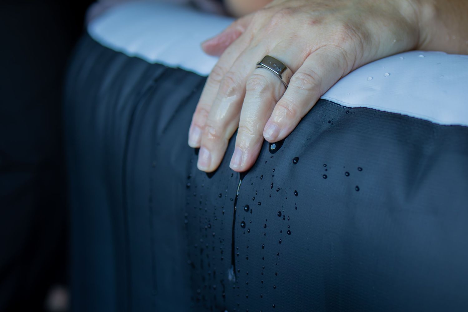 Hand resting gently on dark blue medical examination surface.
