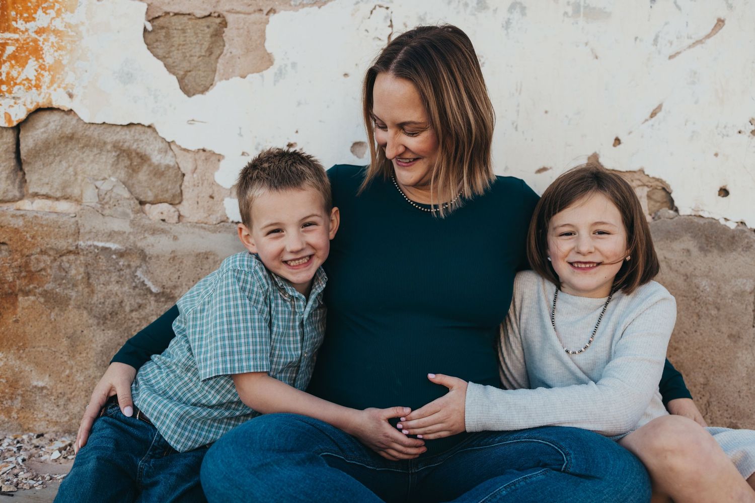 A family sits together and shares joyful moments on a rustic stone wall background.