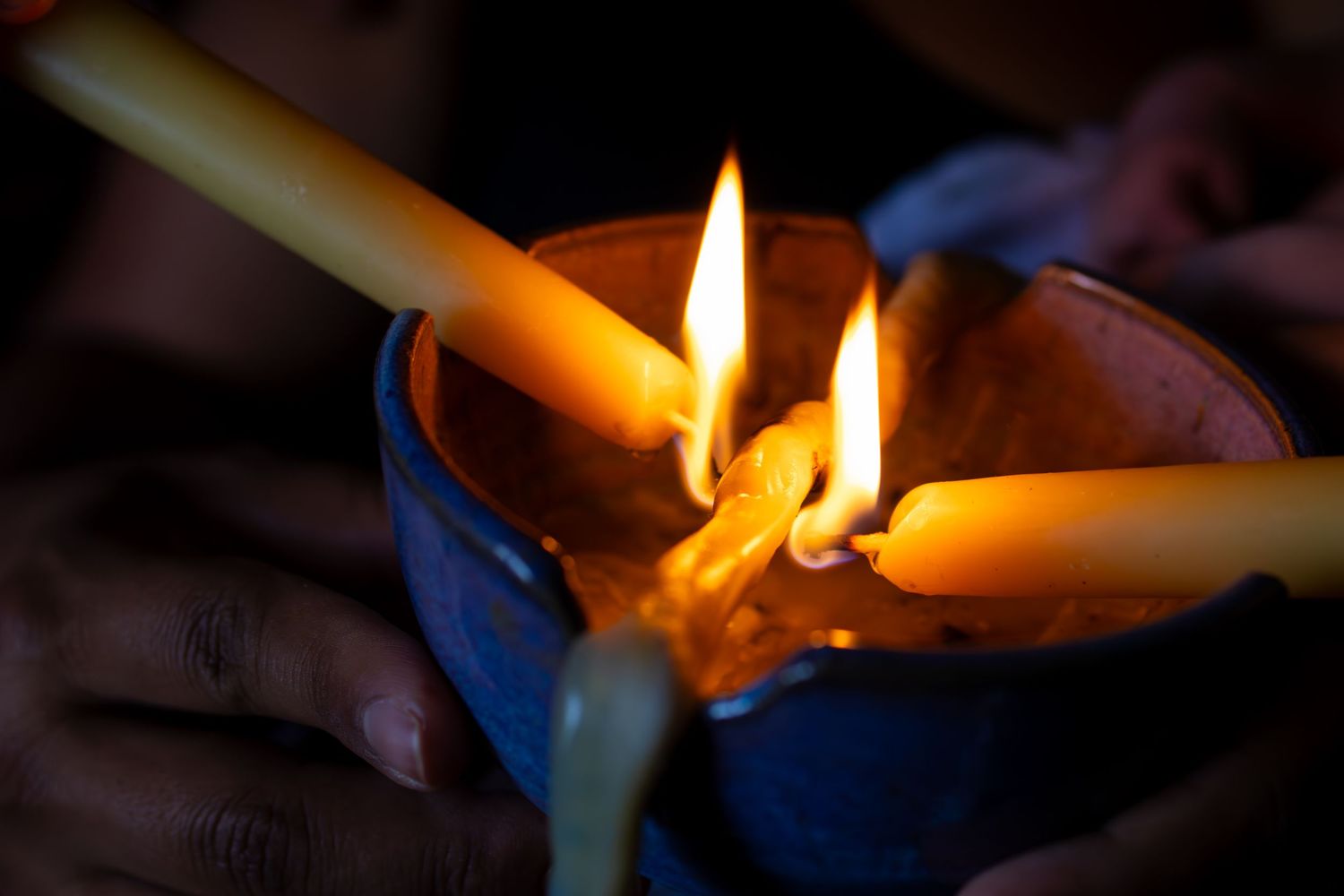Lit candle glowing warmly in darkness with orange flame casting soft illumination. Cord burning ceremony. Home birth photography, Wichita KS