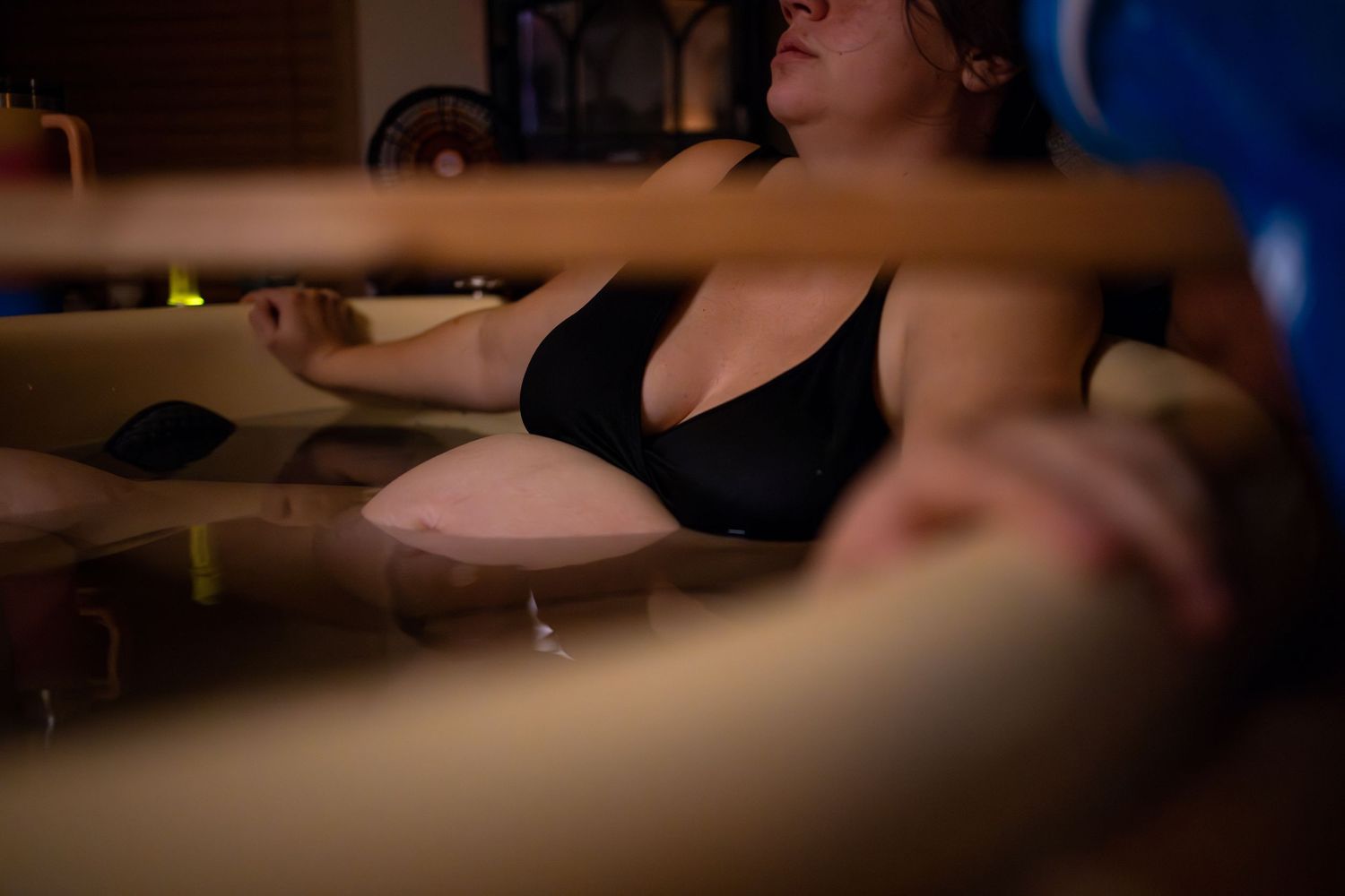 Medical procedure being performed under focused lighting in a clinical setting. Wichita birth photographer documenting a home birth
