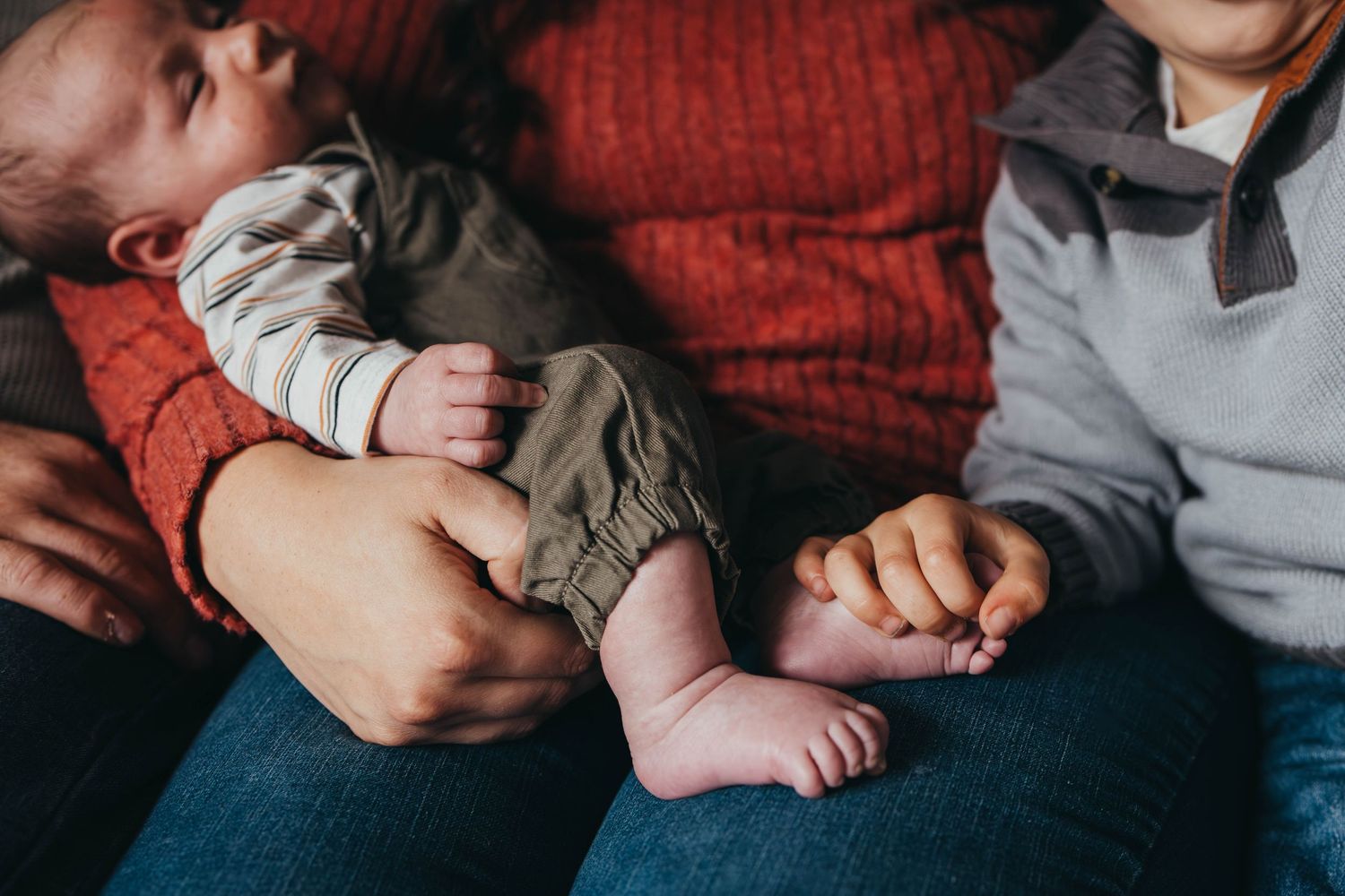 Intimate family moment showing hands and bodies embracing on blue fabric.