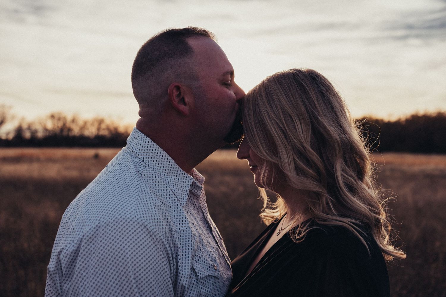 Silhouetted couple embraces during sunset pregnancy photoshoot.
