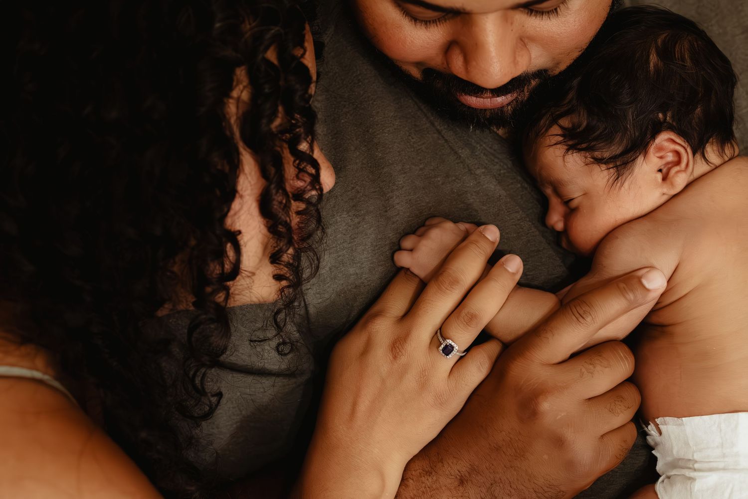 Intimate parenting moment captured in warm, dark tones.