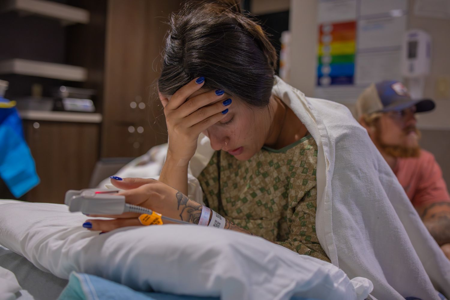 Medical staff attending to a patient in a hospital room with equipment visible.