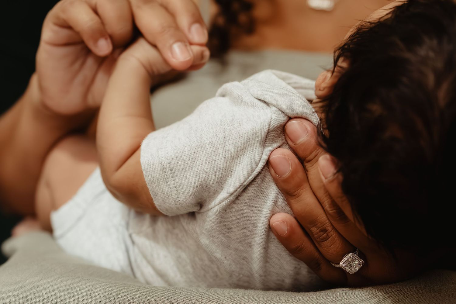 Gentle hands holding small infant feet with delicate toes.