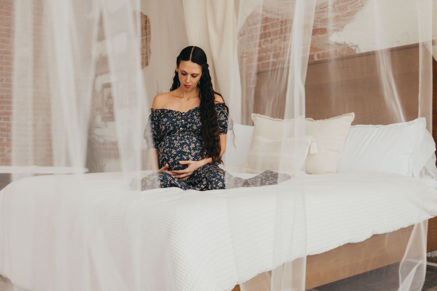 Maternity photography session with flowing white fabric in an outdoor setting.