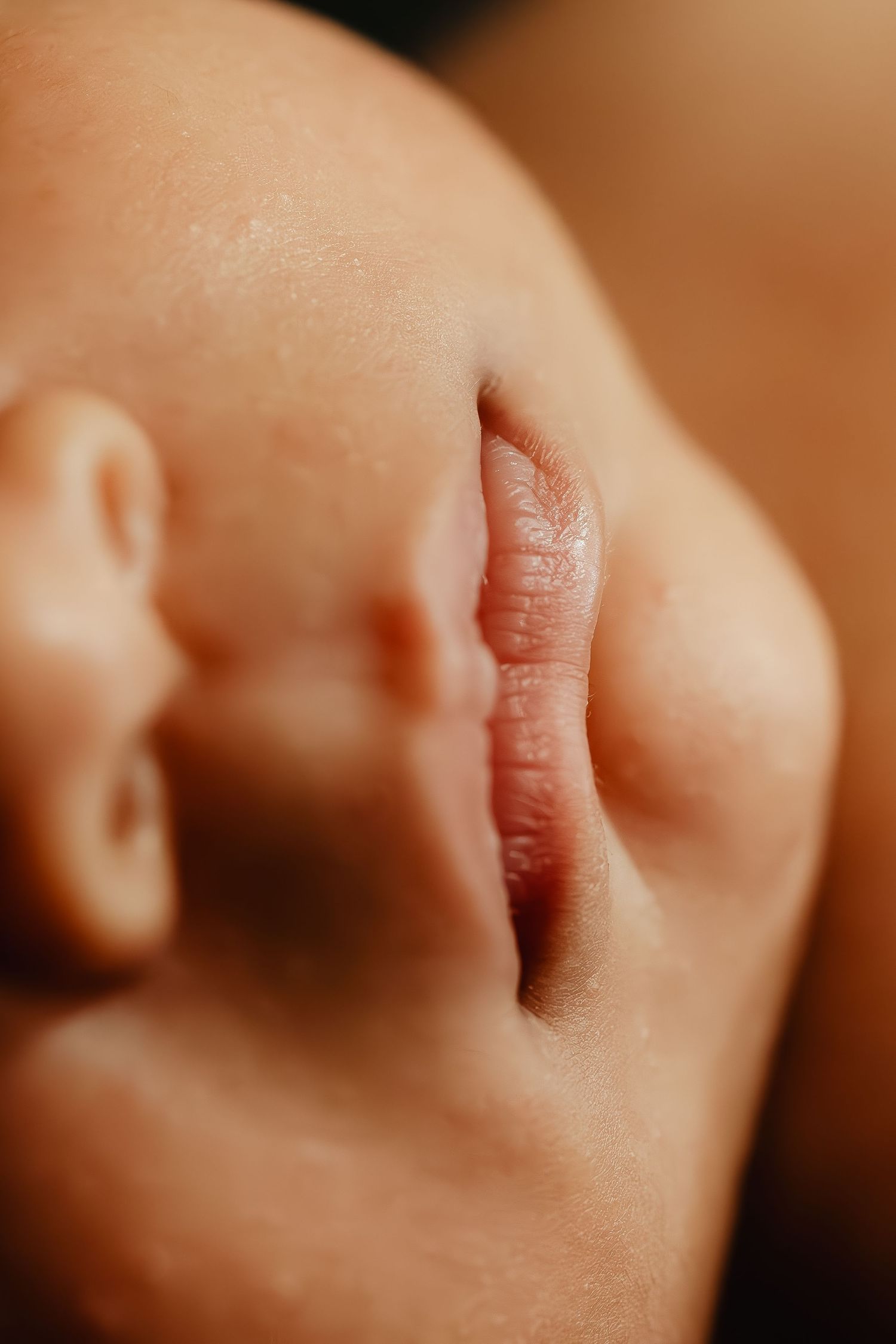 Extreme close-up of baby's lips and cheek in warm tones.