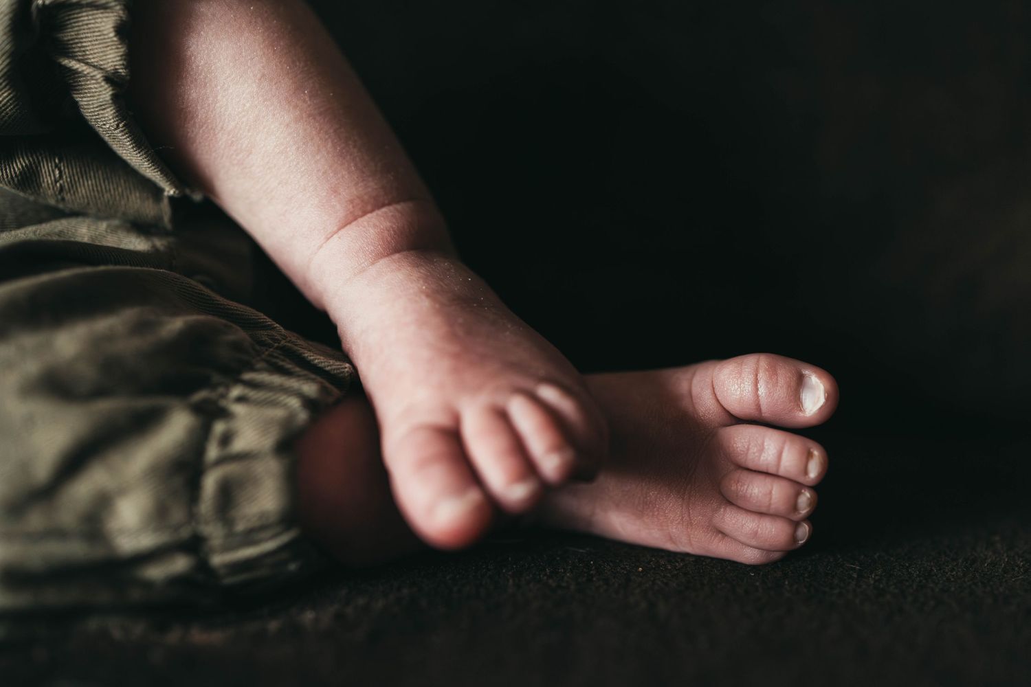 Close-up shot of tiny baby feet against a dark background.
