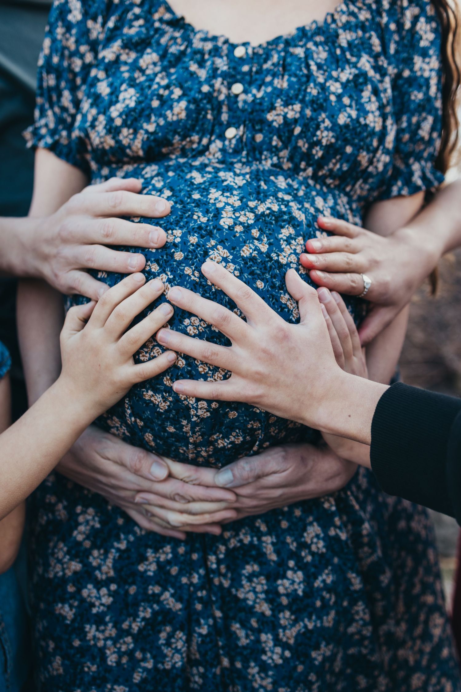 Close-up sequence showing hands lovingly touching a pregnant belly in a blue floral dress.