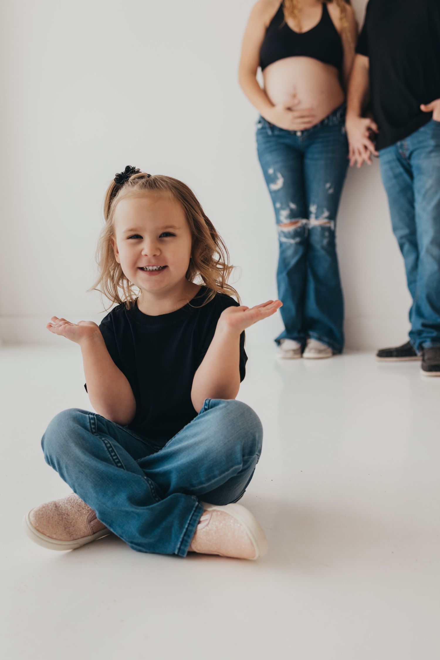 A series of minimalist photos showing a child in blue jeans and black top sitting on a white floor.