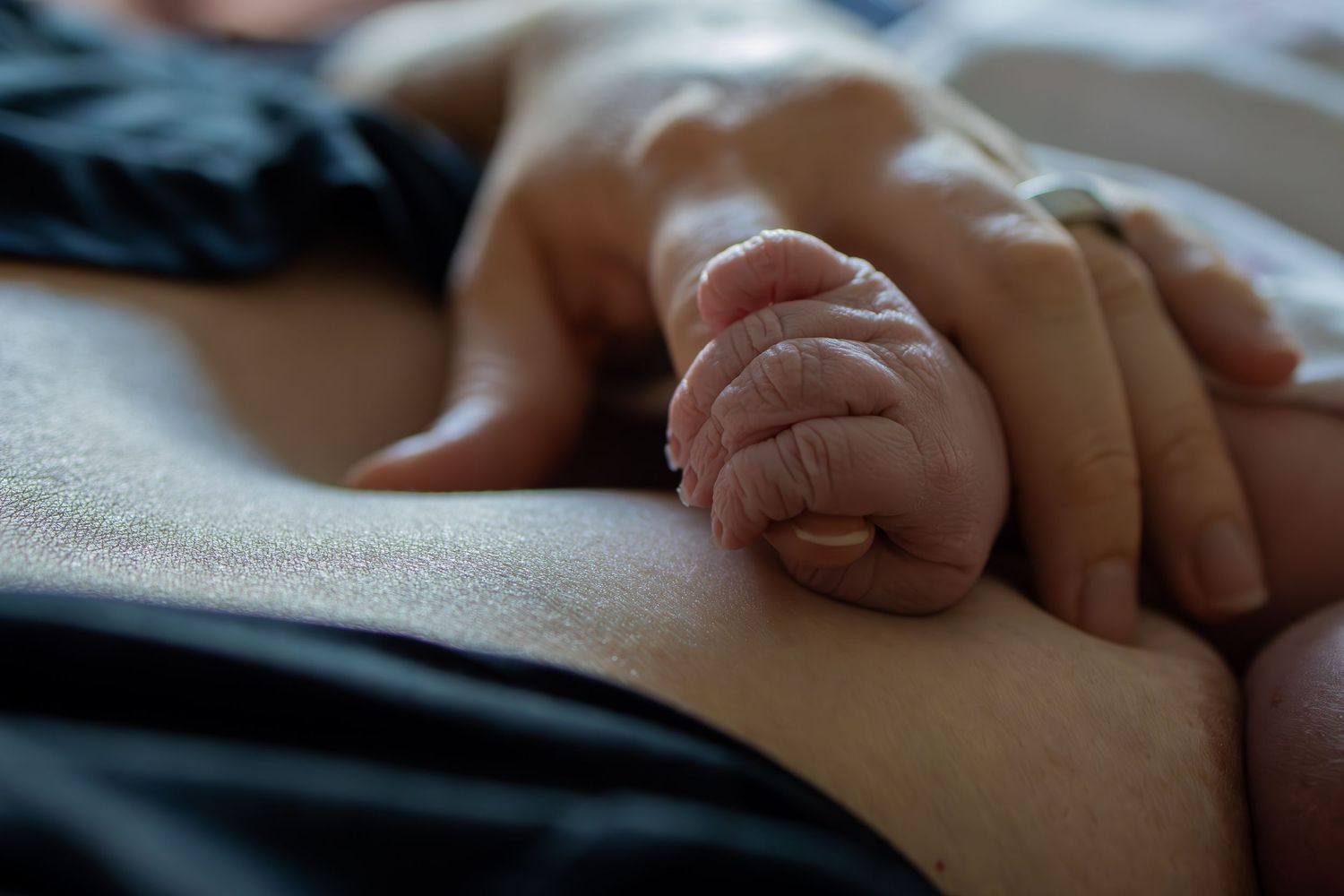 Close-up view of gentle touch during medical examination. Wichita newborn photographer in-home session