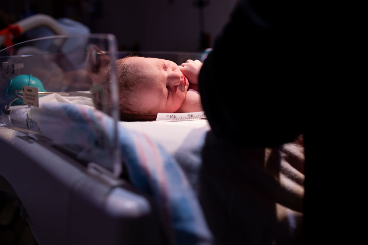 Dimly lit hospital room scene during a medical procedure. Kansas birth photographer capturing labor and delivery