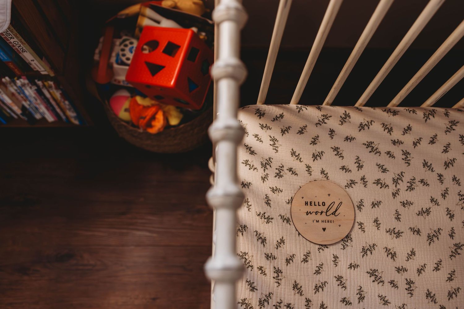 White wooden crib with patterned bedding and nursery decorations.