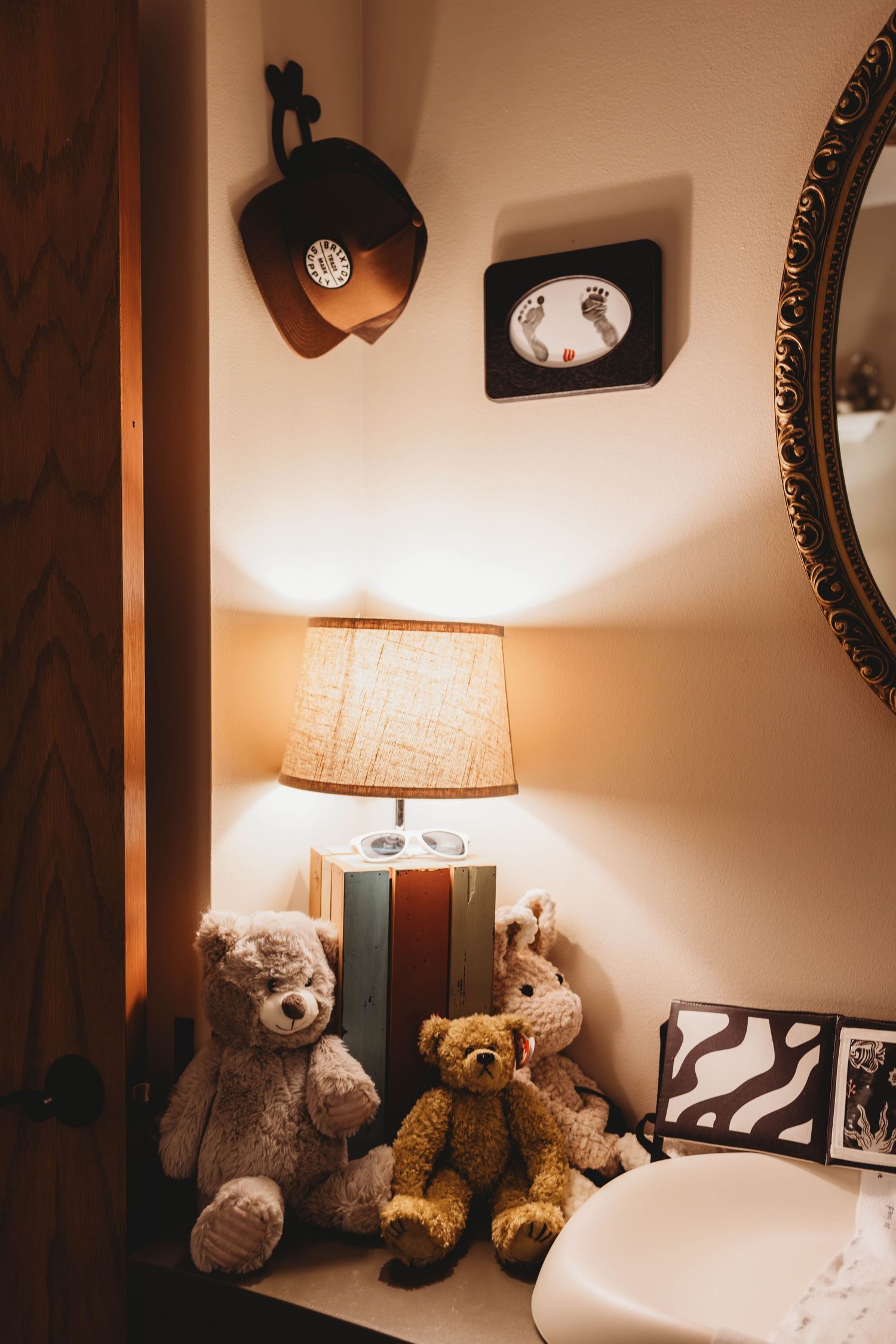 Cozy bedroom corner with teddy bears, table lamp, and vintage wall decor creating a warm ambiance.