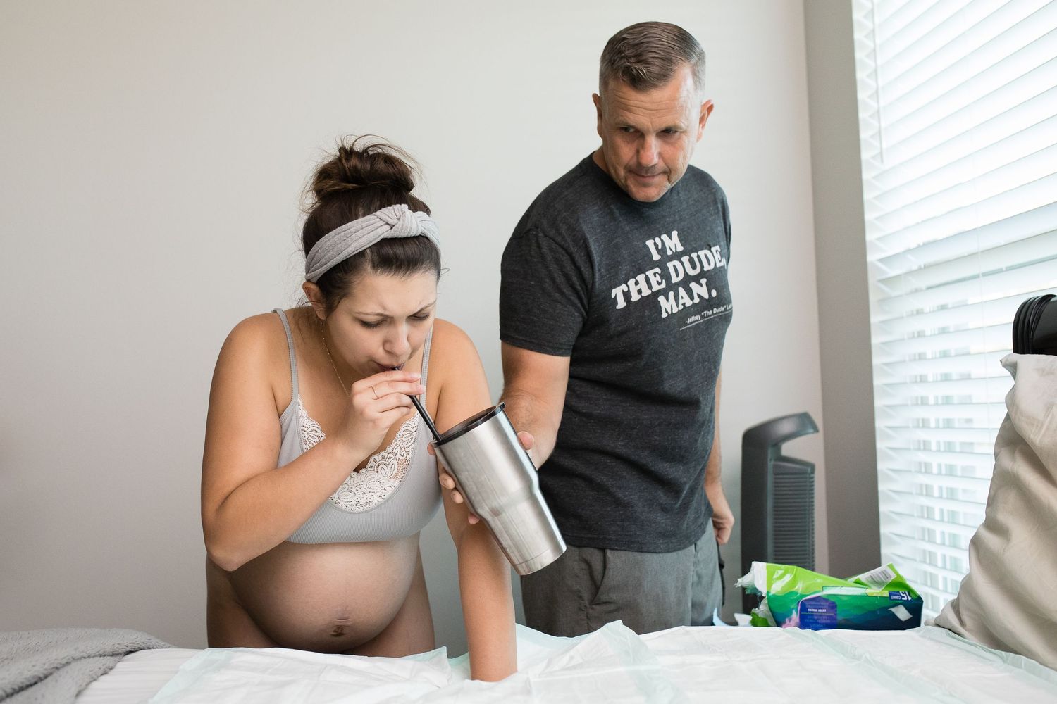 Person in gray top resting on bed during early labor stages.