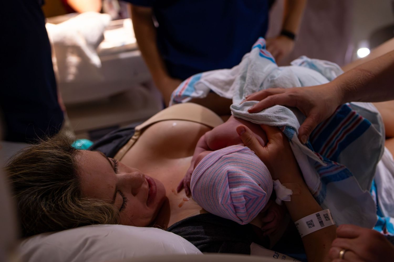 Medical staff attend to a patient lying on a hospital bed during a procedure. Kansas birth photographer capturing labor and delivery.
