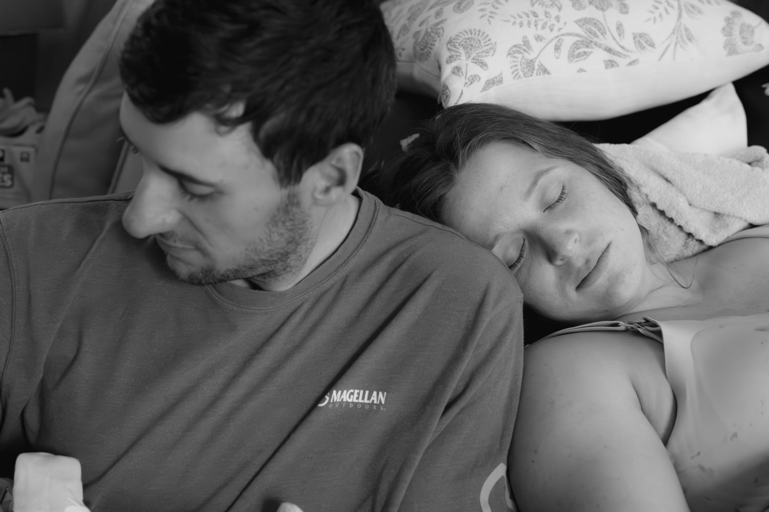 Black and white photo of parents with newborn baby resting.